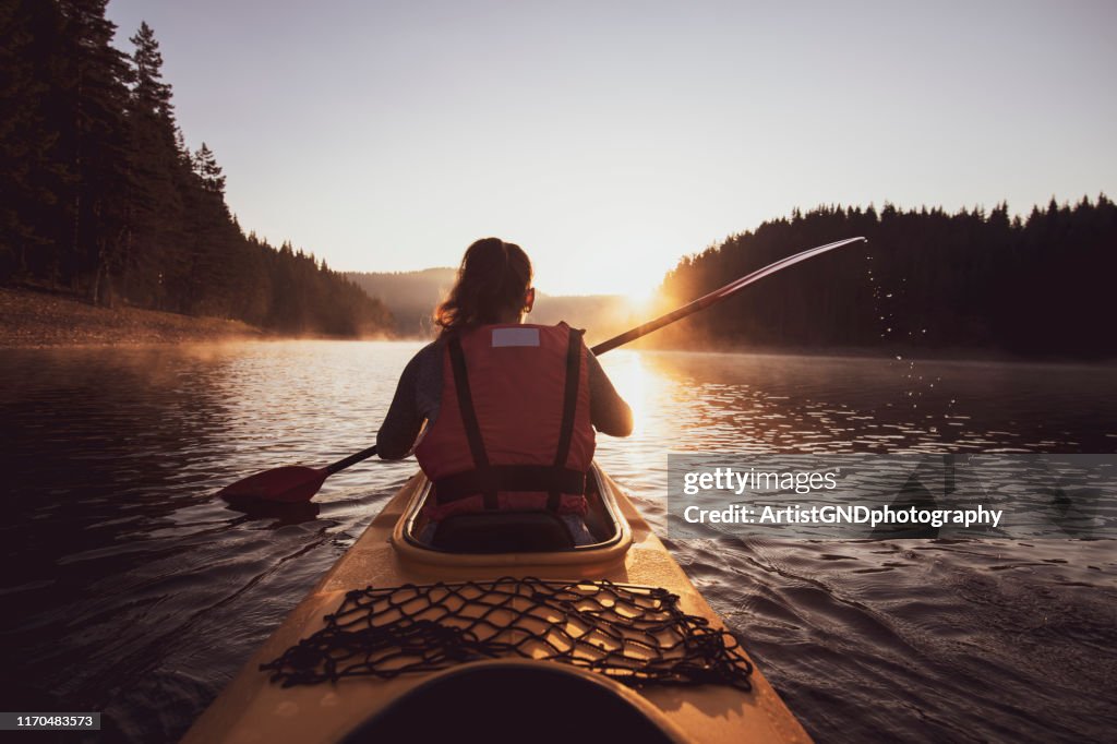 A woman with a kayak at the sunrise.
