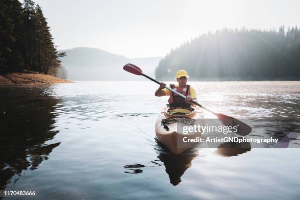 eine frau mit einem kajak bei sonnenaufgang. - kayaker woman stock-fotos und bilder