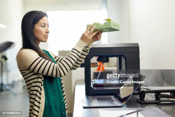 side view of businesswoman examining model while standing by table in office - 3d printer female stock-fotos und bilder