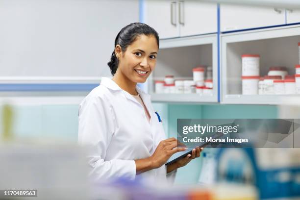 smiling homeopath using digital tablet in hospital - female pharmacist with a digital tablet imagens e fotografias de stock