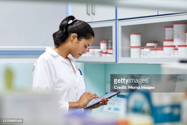 young scientist using digital tablet in hospital - female pharmacist with a digital tablet stock-fotos und bilder