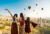 Traveling women looking at air balloons in sky in Cappadocia valley.