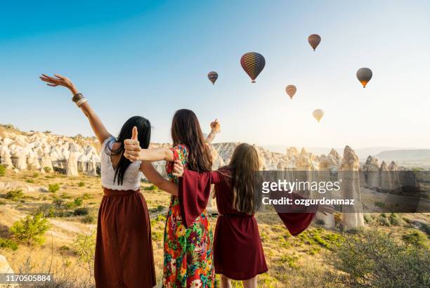 traveling women looking at air balloons in sky in cappadocia valley. - cappadocia hot air balloon stock pictures, royalty-free photos & images