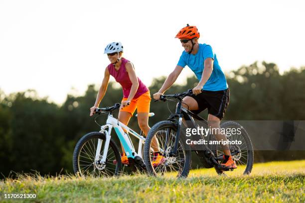 glückliche reife frau und mann radfahren zusammen - e bike stock-fotos und bilder