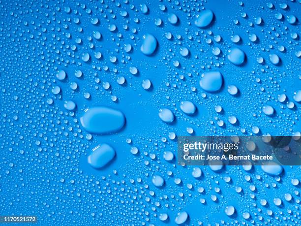 full frame of the textures formed by the bubbles and drops of water, on a blue color background. - rain drops stockfoto's en -beelden