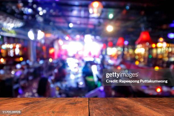 wooden table in front of abstract blurred background of resturant lights - cafe front photos et images de collection