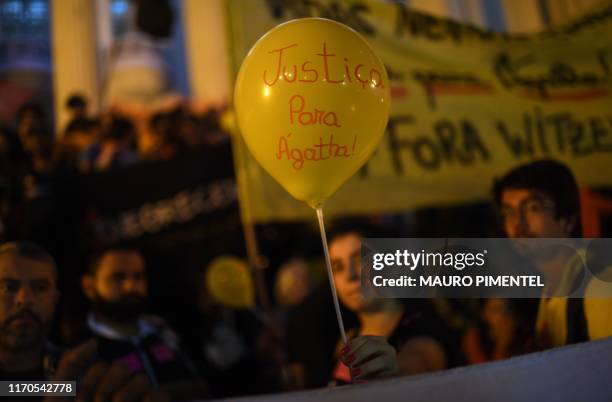 Woman holds a balloon reading "Justice for Agatha" during a demonstration against the recent death of eight-year-old Agatha Sales Felix by a stray...