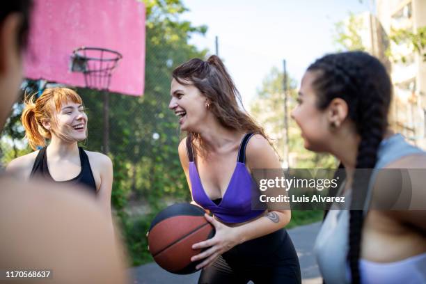 female basketball team talking and smiling on court - womens basketball stock-fotos und bilder