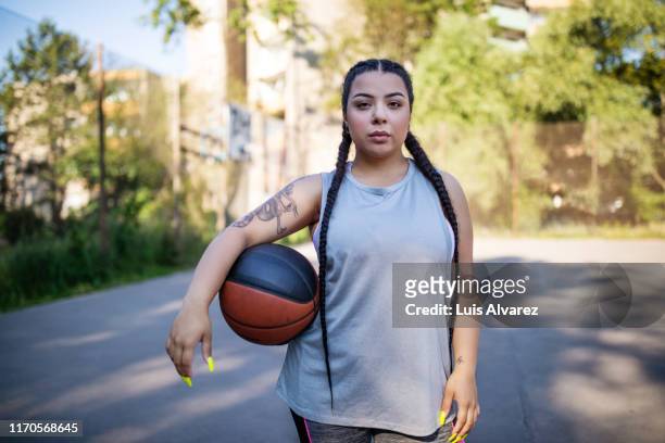 young woman holding basketball on court - basketball sport stock-fotos und bilder