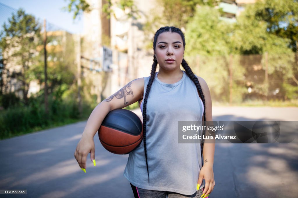 Young woman holding basketball on court