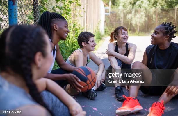 multi-ethnic friends are relaxing after match - street basketball stockfoto's en -beelden