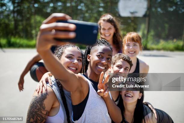 multiracial basketball team taking selfie on court - selfie young people photos et images de collection