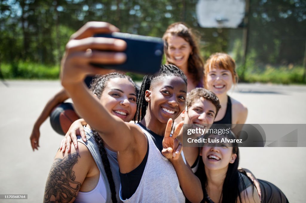 Multiracial basketball team taking selfie on court