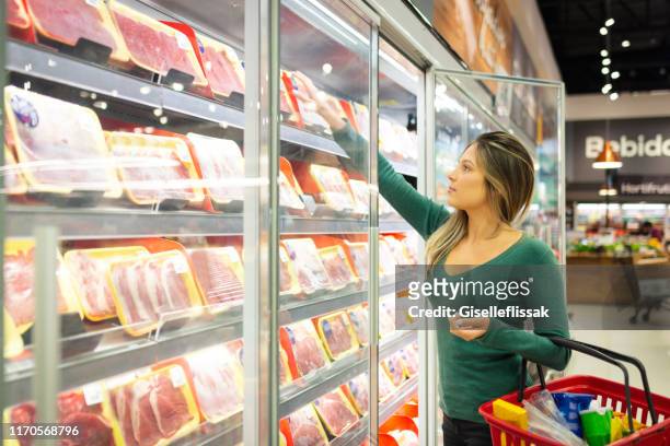 jeune femme dans un supermarché achetant la viande - travée photos et images de collection