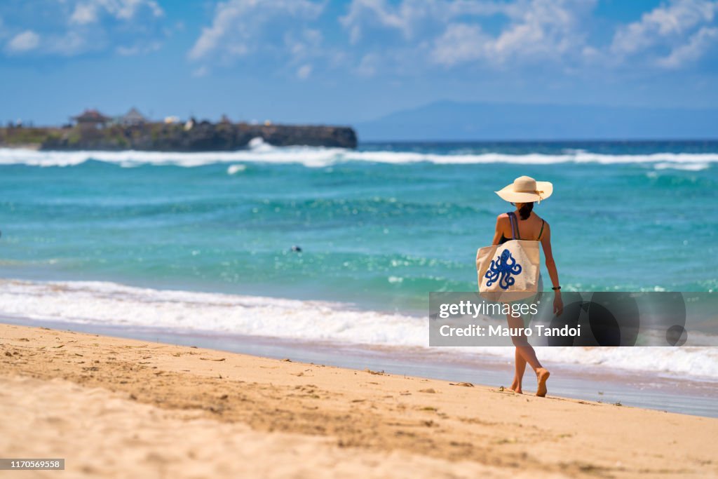 A woman walking nearby to the sea with a beautiful bag, Nusa Dua Beach, Bali, Indonesia