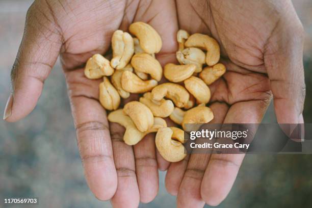 close-up view of hands holding cashews - cashews stock pictures, royalty-free photos & images