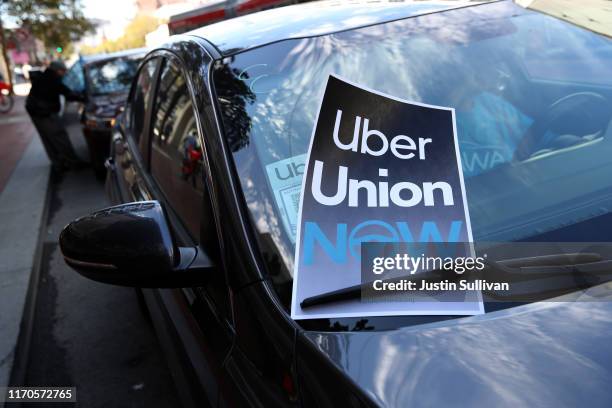 Sign in favor of a union for rideshare drivers sits on a car's windshield during a protest outside of Uber headquarters on August 27, 2019 in San...