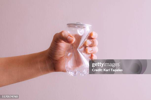 a young person is holding a crumpled plastic and tin soda can on a pink background - reduce stock pictures, royalty-free photos & images