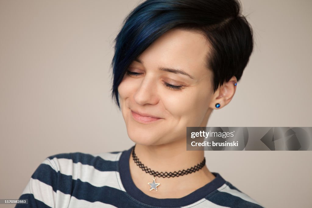 Studio portrait of an attractive 30 year old woman in a striped t-shirt on a beige background