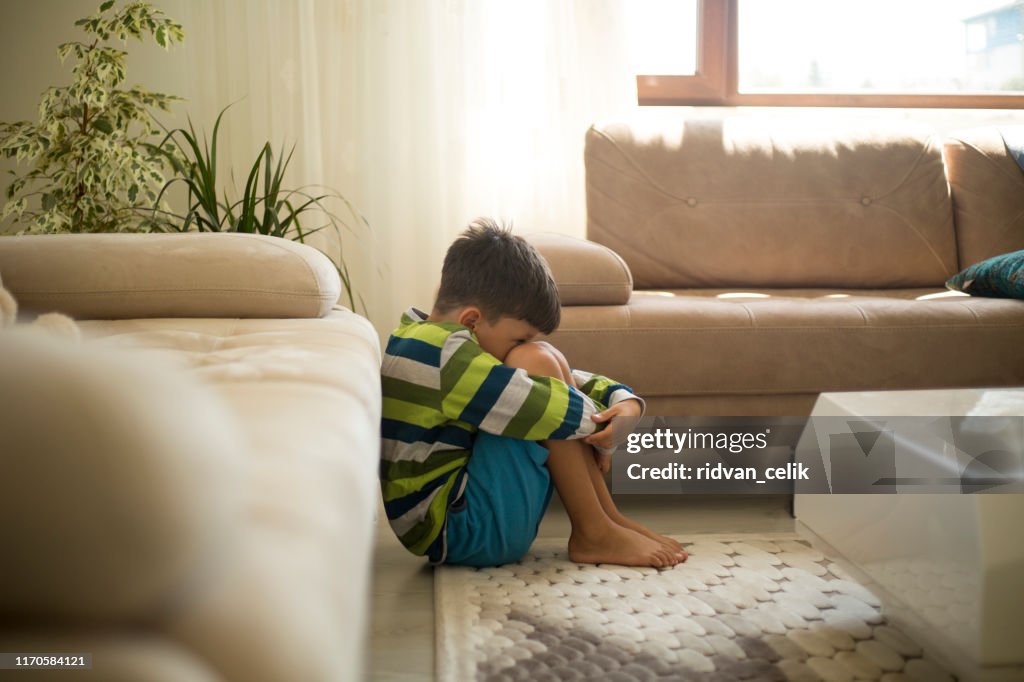 Upset little boy sitting on the floor