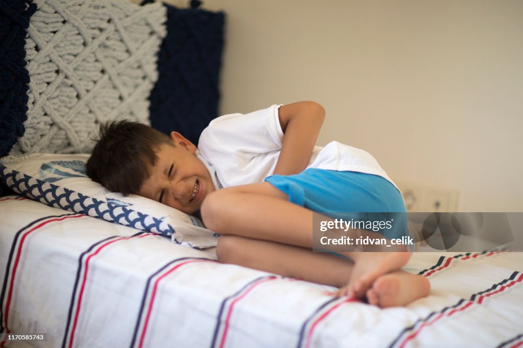 腹痛でベッドに横たわる少年