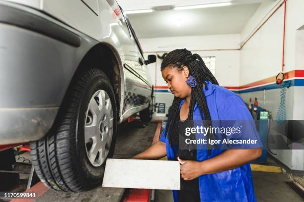 woman mechanic aligning car wheel - giant wheel stock pictures, royalty-free photos & images