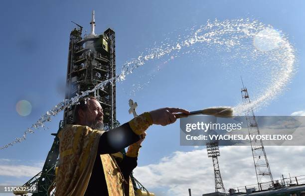 Russian Orthodox priest conducts a blessing in front of the Soyuz booster rocket FG with Soyuz MS-15 spacecraft set on the launch pad of the...