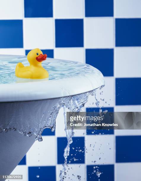 rubber duck in overflowing bath - overlopen stockfoto's en -beelden