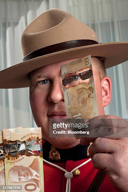 Constable Jeff Reid, a counterfeit investigator for the Royal Canadian Mounted Police, displays $C100 Canadian bank notes for a photograph in...