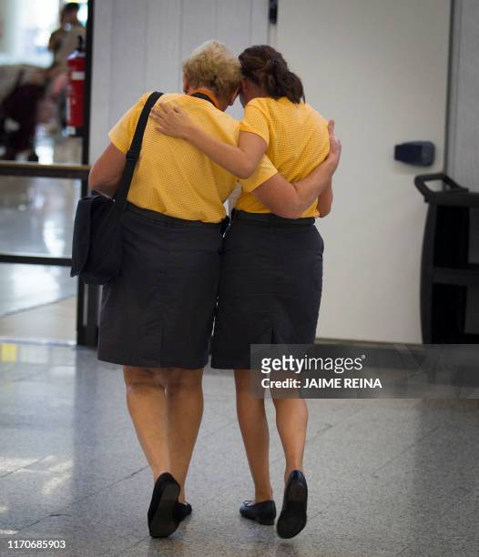 Two workers of British travel group Thomas Cook hug at Son Sant Joan airport in Palma de Mallorca on September 24, 2019. Britain has repatriated ten...