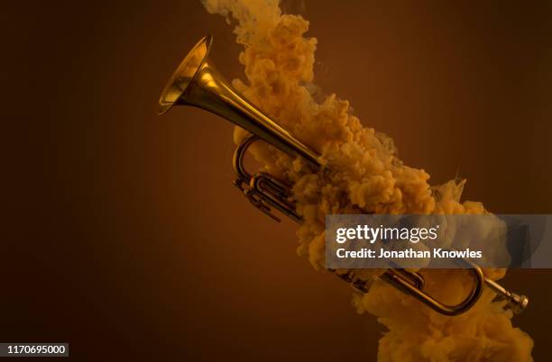 trumpet submerged in liquid with paint clouds - instrumento de metal fotografías e imágenes de stock