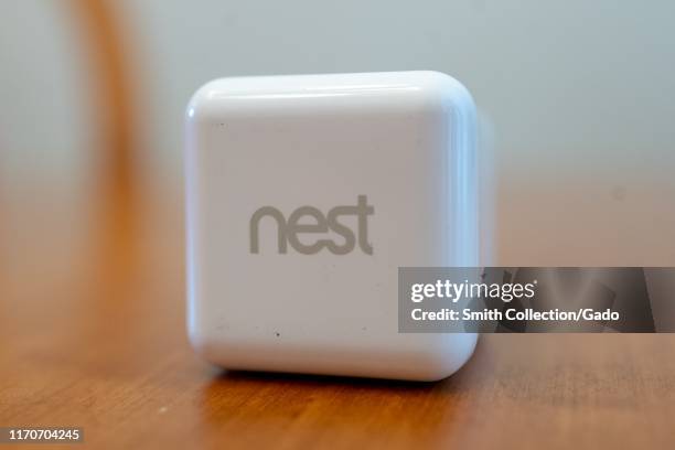 Close-up of logo for Google Inc's Nest line of home security products on a white power supply on light wooden surface in a smart home in San Ramon,...