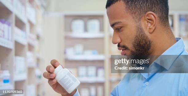 man reading label of medicine bottle - blue pill bottle stock pictures, royalty-free photos & images