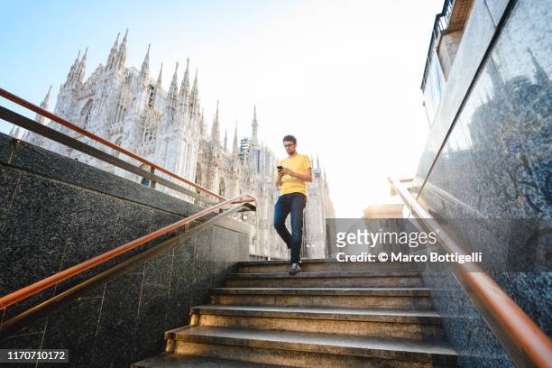 man using smartphone entering the subway in milan, italy - milan photos et images de collection