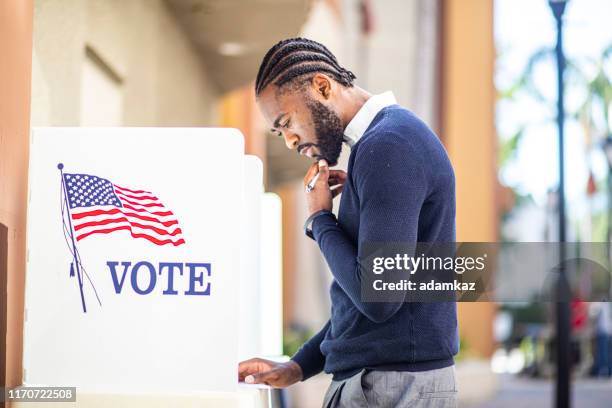 millenial black man voting in election - vote candidate stock pictures, royalty-free photos & images
