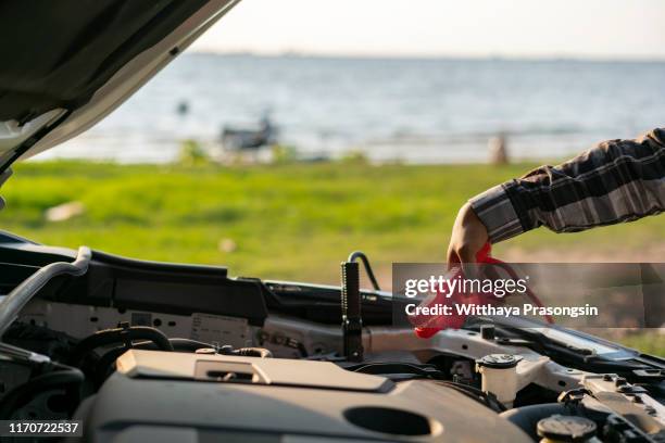 hand charging car battery with electricity trough jumper cables. - car mid air stock pictures, royalty-free photos & images