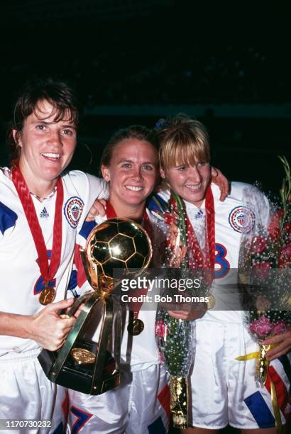 From left, April Heinrichs, Tracey Bates and Shannon Higgins hold up the trophy in celebration after the United States team beat Norway 2-1 in the...