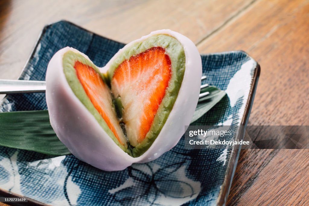 Mochi Japanese dessert with red bean and strawberry fruit ,cute and tasty colorful on wood table.Filter vintage tone