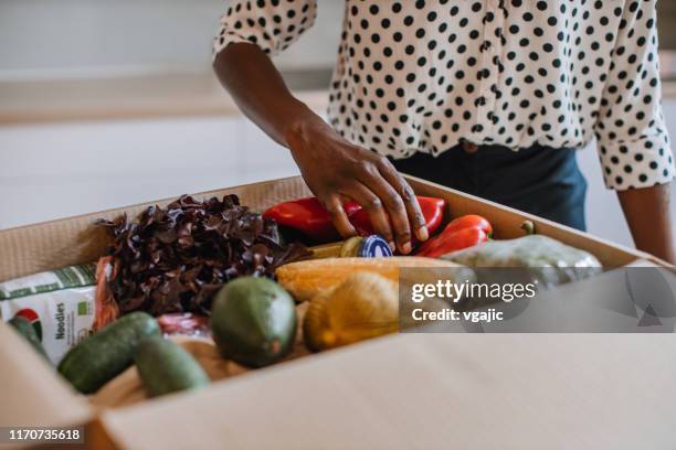 mujer africana que abre parcela con kit de comidas - food delivery fotografías e imágenes de stock