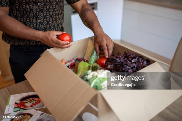 latin man opening parcel with meal kit - meal kit stock pictures, royalty-free photos & images