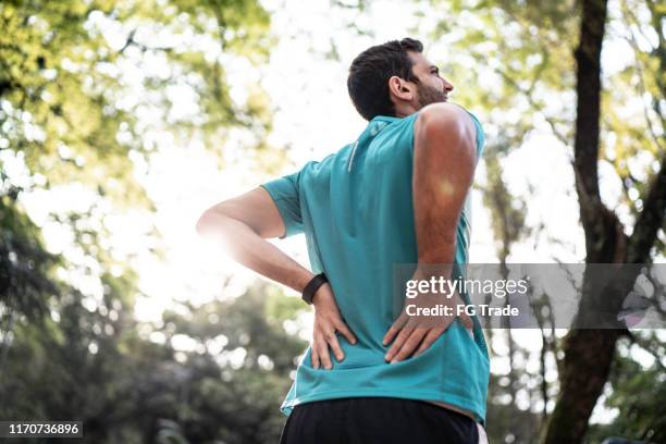 公園で腰痛を感じるスポーツマン - 腰痛 ストックフォトと画像