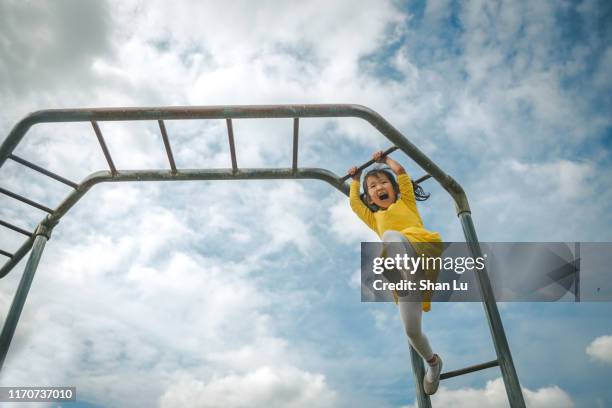 young girl hanging on the monkey bar. - climbing frame stock pictures, royalty-free photos & images