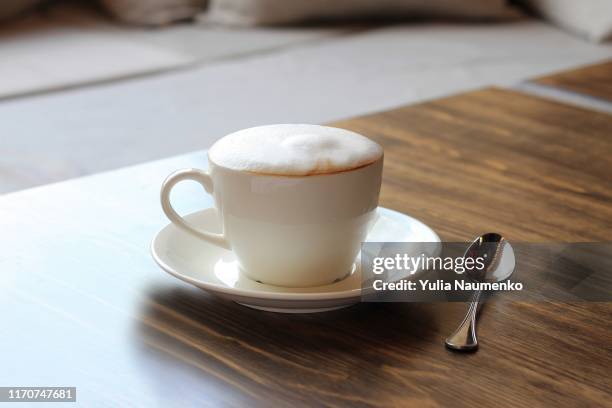 cup of cappuccino on a wooden table in a cafe. beautiful foam, white ceramic cup, copy space. - coffee foam imagens e fotografias de stock