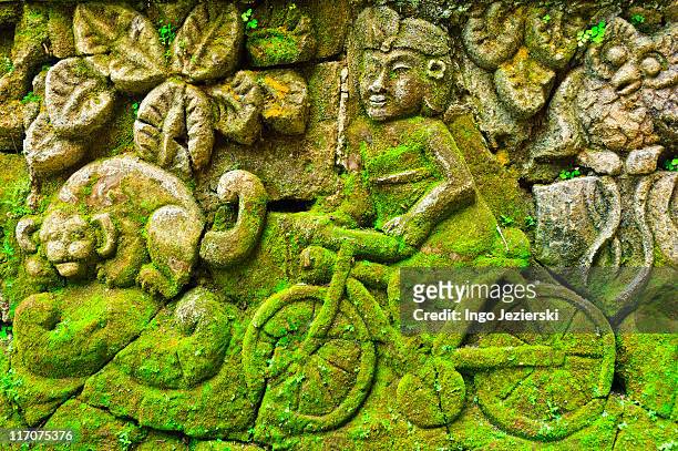 balinese stone relief of cyclist - ubud monkey forest stock pictures, royalty-free photos & images