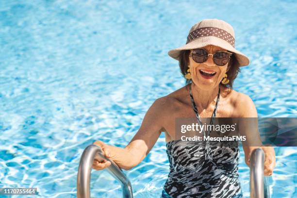 senior redhead woman getting out of the pool - old woman in swimsuit imagens e fotografias de stock