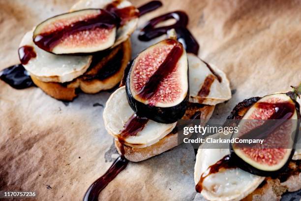 frische feigen mit geschmolzenem ziegenkäse und balsamico-essig auf geröstetem brot. - ziegenkäse stock-fotos und bilder