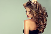 Young, brown haired woman is touching softly owne hair. Hair care.