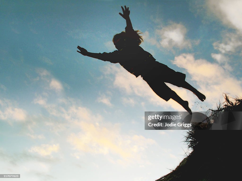 Silhouette child Jumping off sand dune