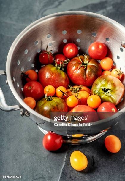 heirloom tomatoes in a colander on black background - passoire photos et images de collection