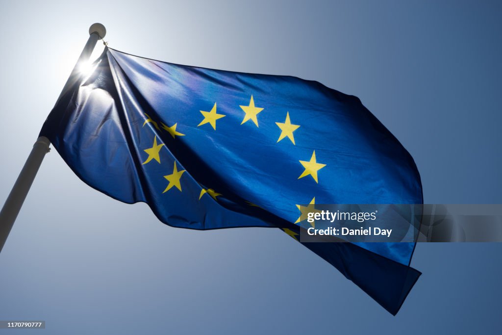 Series of images of the EU flag flying in the wind, backlight and blue sky